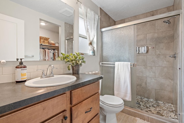 full bathroom with vanity, a spacious closet, a shower stall, and toilet