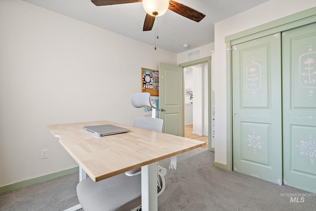 office area with light carpet, visible vents, a ceiling fan, and baseboards