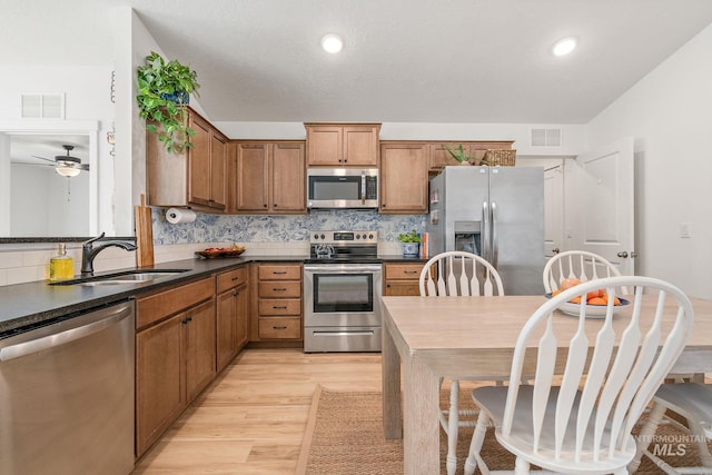 kitchen with a sink, visible vents, appliances with stainless steel finishes, tasteful backsplash, and dark countertops