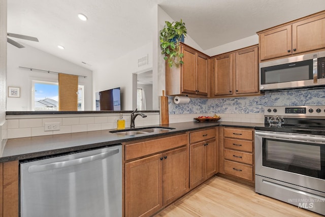 kitchen featuring stainless steel appliances, vaulted ceiling, visible vents, and a sink