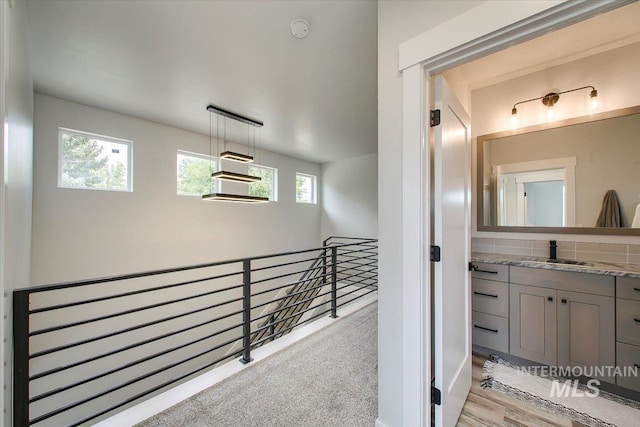 hall featuring sink and light carpet