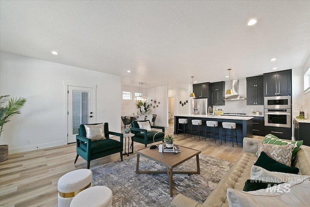 living room with sink, light hardwood / wood-style flooring, and a textured ceiling