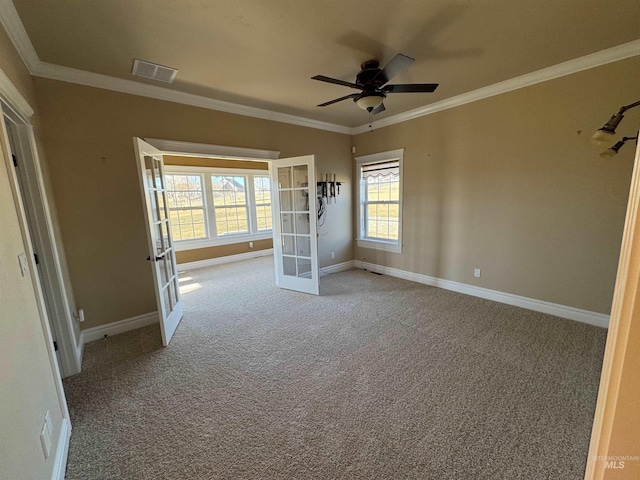 carpeted empty room featuring french doors, visible vents, crown molding, and baseboards