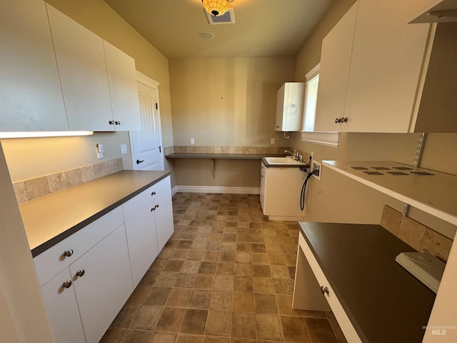 kitchen with light countertops, stone finish floor, white cabinets, and a sink