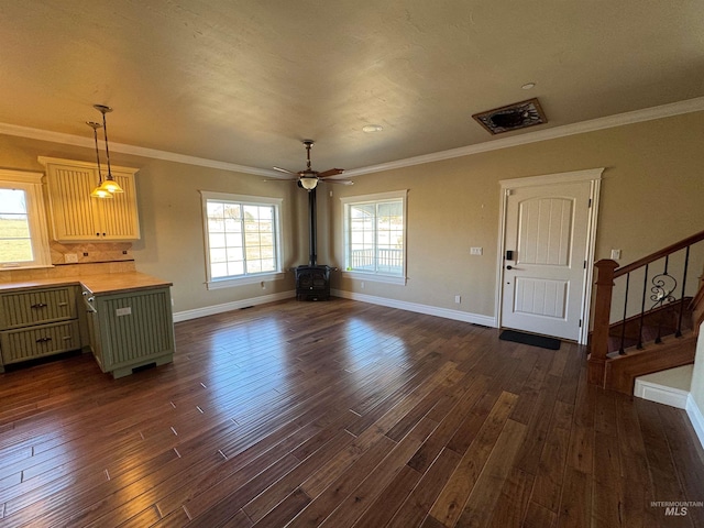 unfurnished dining area with a wood stove, dark wood-style floors, stairway, and a wealth of natural light