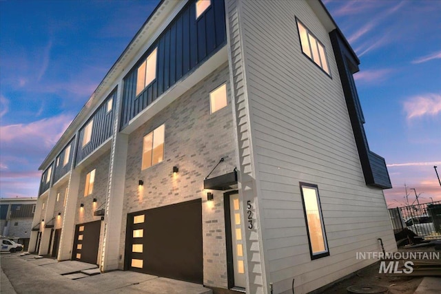 property exterior at dusk featuring a garage and board and batten siding