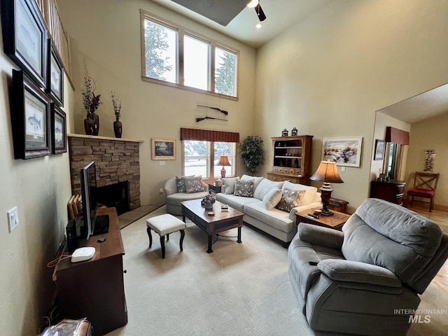 living room with light carpet, a fireplace, ceiling fan, and a high ceiling