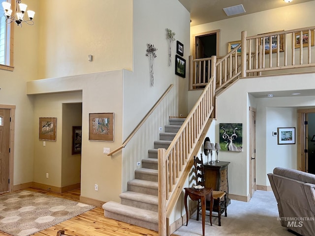 staircase with a chandelier, hardwood / wood-style floors, and a high ceiling