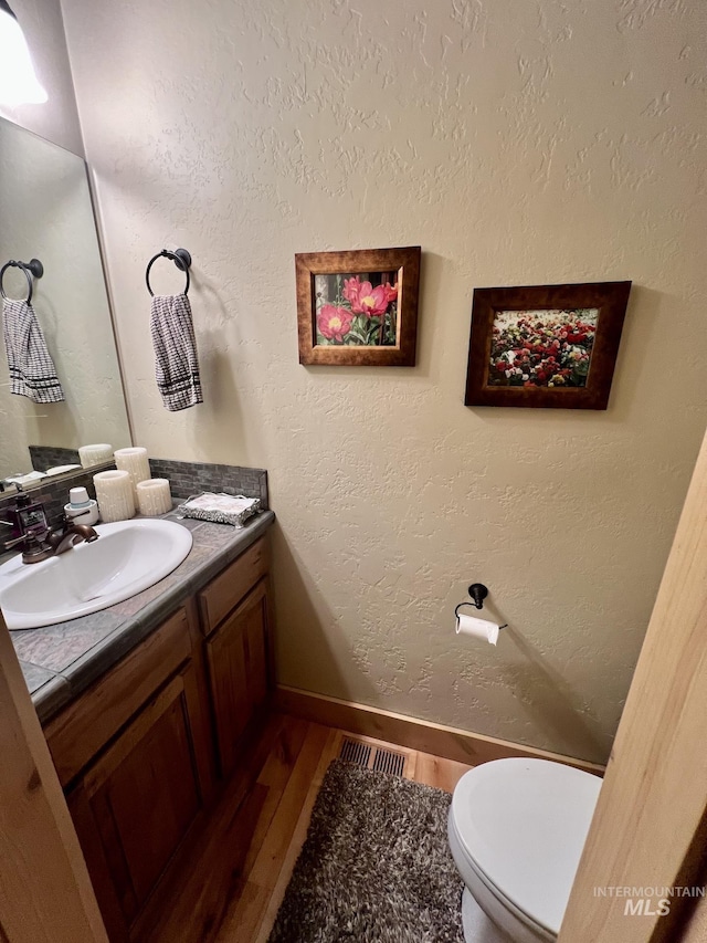 bathroom with vanity, hardwood / wood-style flooring, and toilet