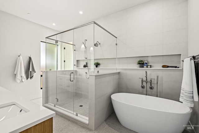 bathroom with shower with separate bathtub, vanity, and tile walls