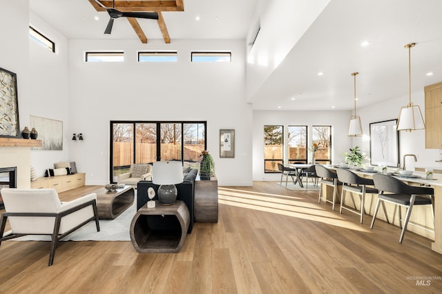 living room with a high ceiling, light wood-type flooring, and ceiling fan