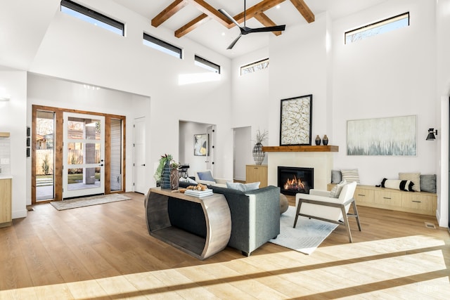 living room with plenty of natural light, ceiling fan, a towering ceiling, and light hardwood / wood-style flooring