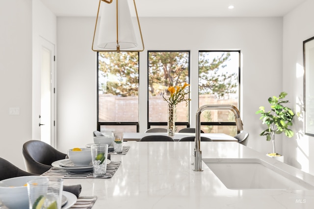 kitchen with light stone countertops, sink, and hanging light fixtures