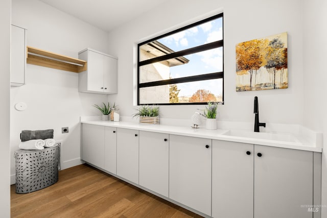 interior space with white cabinetry, sink, and light hardwood / wood-style flooring