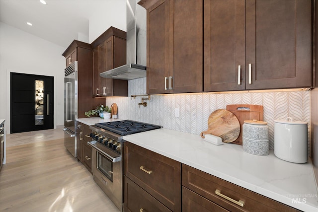 1678 Majestic View Dr, Mccall, ID 83638 - kitchen with high end appliances, wall chimney range hood, tasteful backsplash, light wood finished floors, and dark brown cabinets