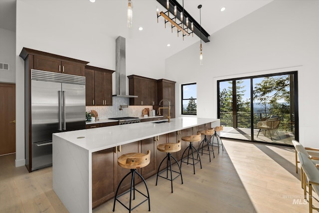 1678 Majestic View Dr, Mccall, ID 83638 - kitchen featuring built in refrigerator, high vaulted ceiling, wall chimney exhaust hood, light wood-style flooring, and tasteful backsplash
