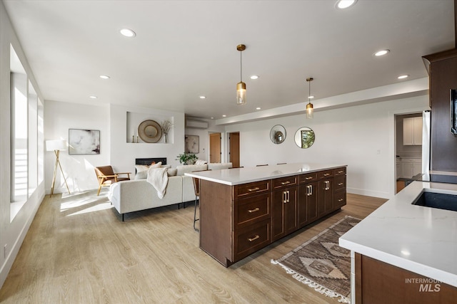 1678 Majestic View Dr, Mccall, ID 83638 - kitchen featuring light countertops, light wood-type flooring, a wall mounted air conditioner, a glass covered fireplace, and recessed lighting