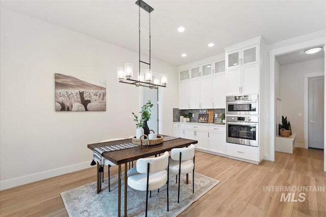6874 N Fireball, Meridian, ID 83646 - kitchen featuring stainless steel double oven, light wood-style floors, baseboards, decorative backsplash, and white cabinetry