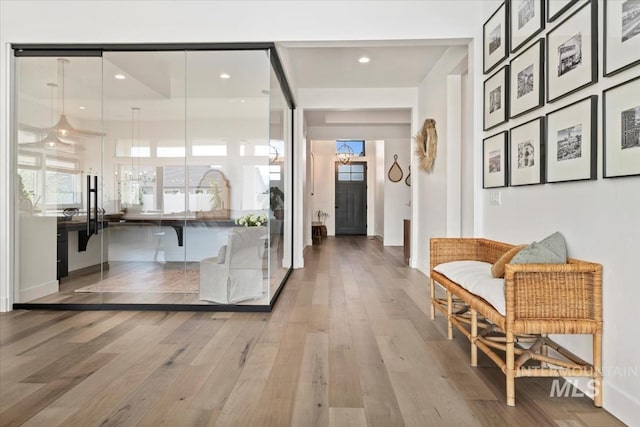 corridor with wood finished floors, healthy amount of natural light, baseboards, and recessed lighting