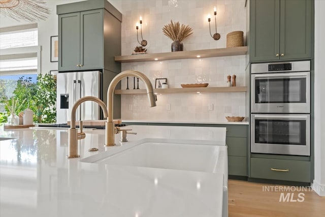 kitchen featuring green cabinets, stainless steel appliances, tasteful backsplash, and open shelves