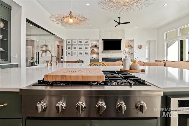 kitchen featuring open floor plan, a sink, ceiling fan, a fireplace, and recessed lighting