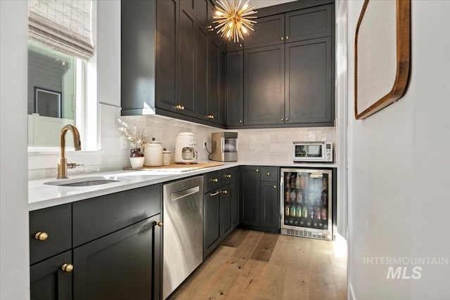 kitchen with stainless steel dishwasher, beverage cooler, a sink, light wood-style floors, and light countertops