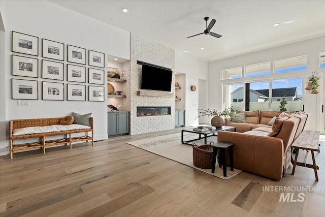 living area with light wood finished floors, a large fireplace, a ceiling fan, and recessed lighting