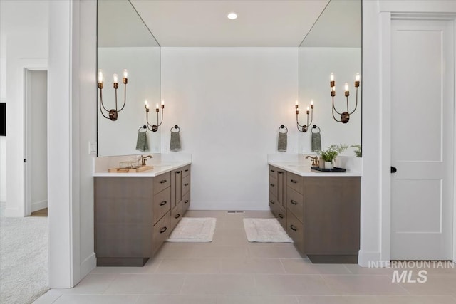 full bathroom with two vanities, a chandelier, and tile patterned flooring
