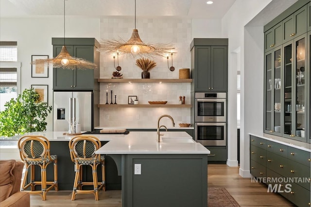 kitchen with appliances with stainless steel finishes, a sink, green cabinets, decorative backsplash, and recessed lighting