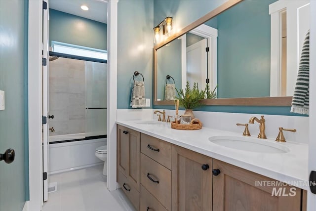 full bathroom with toilet, double vanity, bath / shower combo with glass door, and tile patterned flooring