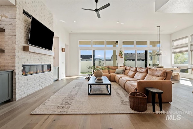 living area with hardwood / wood-style flooring, a fireplace, ceiling fan, recessed lighting, and a chandelier