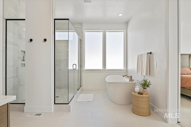 ensuite bathroom with baseboards, a stall shower, and a freestanding bath