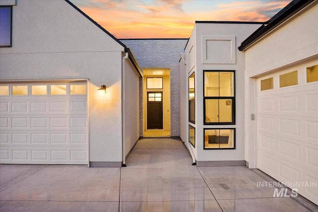 exterior entry at dusk featuring stucco siding
