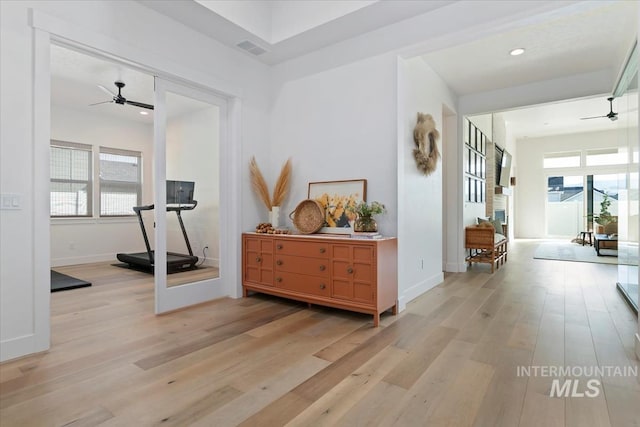 corridor featuring light wood-style flooring, baseboards, and recessed lighting