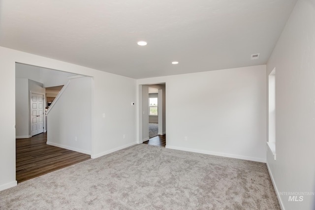 spare room featuring dark colored carpet, visible vents, baseboards, and recessed lighting