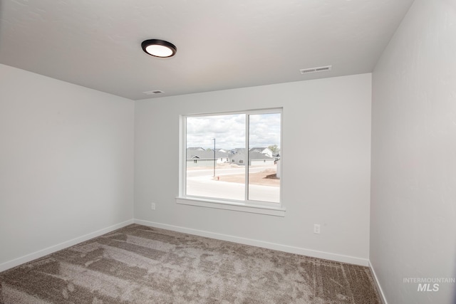 unfurnished room featuring carpet, visible vents, and baseboards