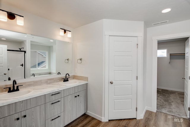 bathroom with double vanity, visible vents, a sink, and wood finished floors