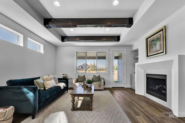 living room with a wealth of natural light, built in features, wood-type flooring, and a textured ceiling