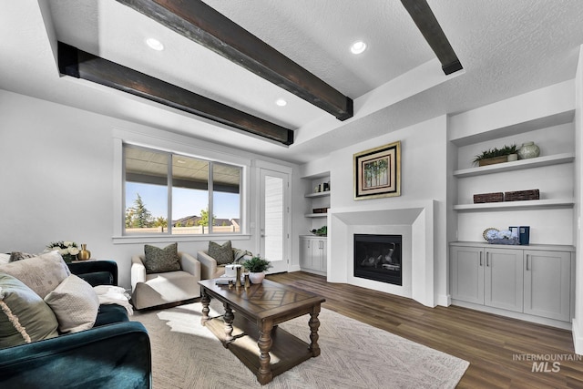 living room featuring beamed ceiling, dark hardwood / wood-style floors, built in features, and a textured ceiling