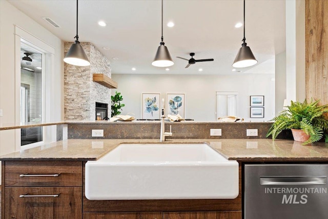 interior space with ceiling fan, hanging light fixtures, sink, dishwasher, and a fireplace