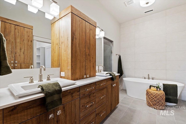 bathroom featuring tile walls, tile patterned flooring, vanity, and a tub