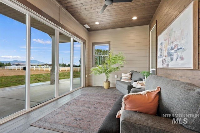 sunroom / solarium featuring ceiling fan, a mountain view, and wood ceiling