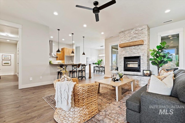 living room featuring ceiling fan, hardwood / wood-style flooring, and a fireplace