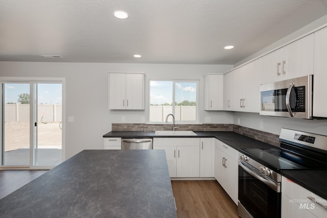 kitchen featuring dark hardwood / wood-style flooring, sink, white cabinets, and appliances with stainless steel finishes