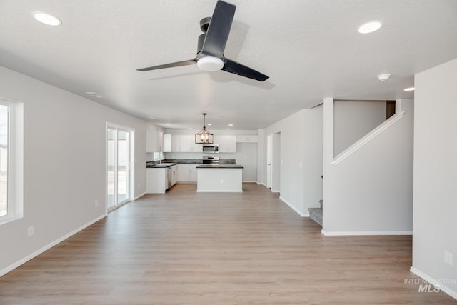 unfurnished living room with a textured ceiling, light hardwood / wood-style flooring, and ceiling fan