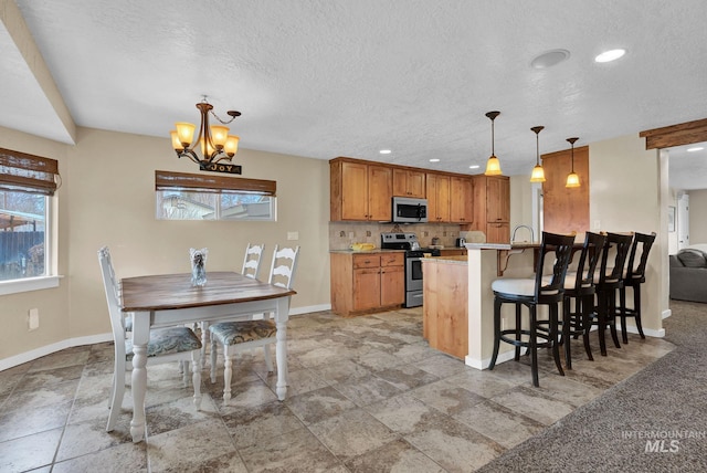 kitchen featuring stainless steel appliances, decorative light fixtures, a kitchen breakfast bar, tasteful backsplash, and a notable chandelier