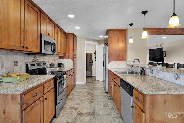 kitchen with sink, decorative light fixtures, light stone countertops, and appliances with stainless steel finishes