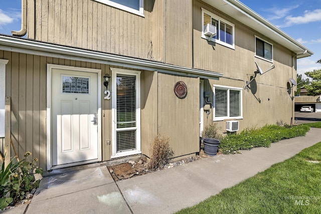 view of exterior entry with cooling unit and an AC wall unit