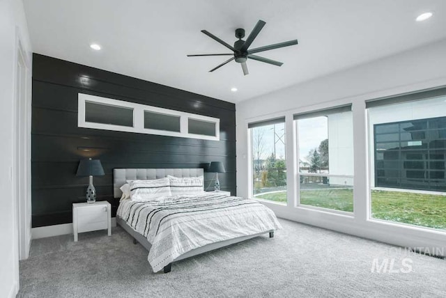 bedroom with wood walls, ceiling fan, and carpet flooring