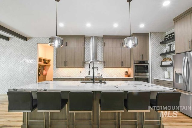 kitchen with appliances with stainless steel finishes, beamed ceiling, pendant lighting, and wall chimney range hood